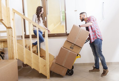 Professional movers carrying furniture through a Brixton flat staircase